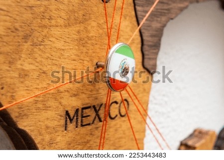 Mexico flag on the pushpin with red thread showed the paths of movement or areas of influence in the global economy on the wooden map. Planning of traveling or logistic concept. Network connection. 