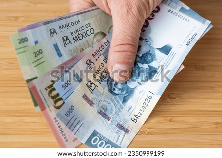 Mexico money held in hand, various pesos banknotes