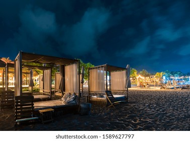 Mexico, Puerto Escondido, Night Vision Of Schalets On The Beach, Wooden Canopy Beds In The Foreground, Lights And Palm Trees In The Background