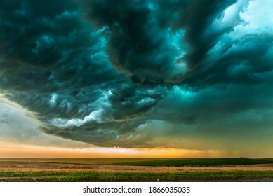 A mezocyclone storm with dark, gray clouds forming over the plains in Tornado Alley, Oklahoma at sunset