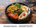 MEZZE PLATTER or mezzeh hummus, vine leaves, tabouleh, baba ganoush, lemon, mutabal served in dish isolated on background top view of arabic food