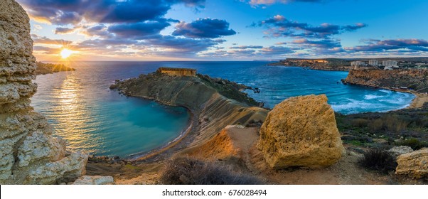 Mgarr, Malta - Panorama of Gnejna bay and Golden Bay, the two most beautiful beaches in Malta at sunset with beautiful colorful sky and golden rocks taken from Ta Lippija