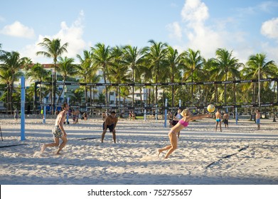 MIAMI - August 31, 2017: Athletic woman digs out a serve while playing volleyball on the Miami Beach promenade with backdrop of iconic art-deco buildings and palm trees of Lumus Park on Ocean Drive