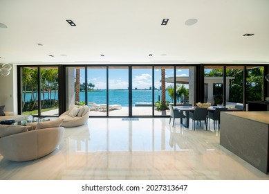Miami Beach - April 2019: Modern living and dining areas with wide views of the bay and city. Beautiful minimalist white interior