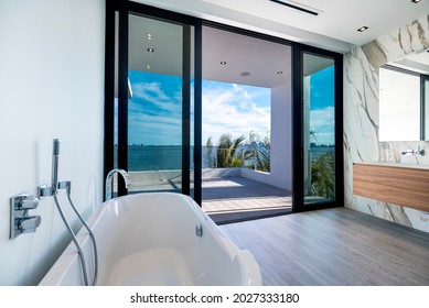 Miami Beach - April 2020: Bathtub inside spacious bathroom with view of outside bay. Daytime shot of luxury home.