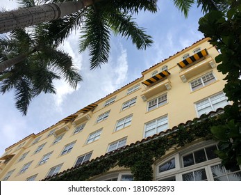 Miami Beach, FL - September 6th, 2020: Upward Shot Of Historical Mediterranean Revival Architecture On Collins Avenue And 13th Street, South Beach. Yellow Facade With Blue Sky, Framed By Palm Trees.