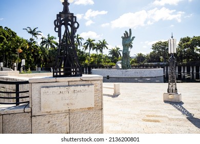 MIAMI BEACH, FL, USA - OCTOBER 14, 2019: The Holocaust Memorial In Miami Beach Features A Reflection Pool With A Hand Reaching Up And Bodies Climbing,  A Memorial Wall, And Memorial Bridge.