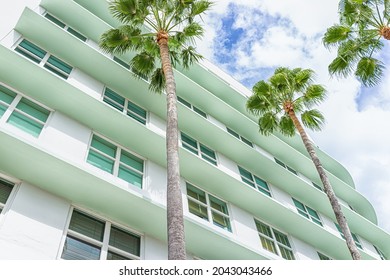 Miami Beach, Florida colorful pastel green house apartment building with Art Deco district style architecture looking up on palm trees and windows