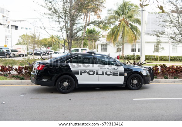 Miami beach , Florida - December\
17, 2015: Police car with emergency vehicle lighting standing on\
road near at Miami beach with palm trees sunny summer\
day