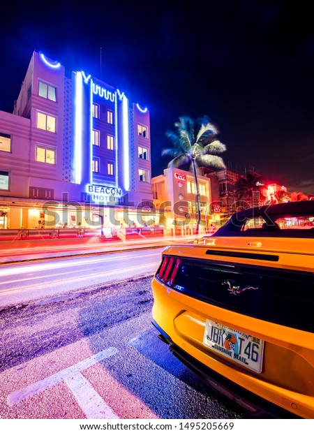 MIAMI BEACH, FLORIDA, USA – AUGUST 2019: Beautiful\
colorful color street in Miami Beach, Miami city Florida, USA 2019.\
Hotels on Ocean Drive. Beautiful expensive sports car on the\
background of hotels
