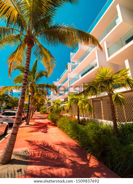 MIAMI BEACH, FLORIDA, USA – AUGUST\
2019: Beautiful residential complex in Miami Beach. Beautiful\
apartment building with modern balconies next to palm\
trees
