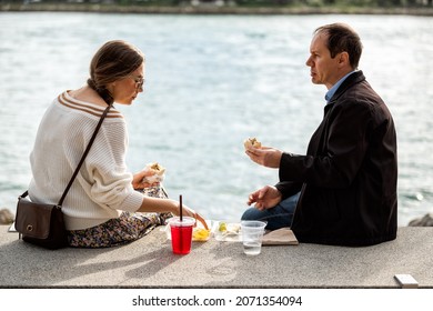 Miami Beach, USA - January 17, 2021: South Pointe Park With Candid Two People Sitting At Bay Water In Miami, Florida Eating Lunch Food Sandwiches And Drinks