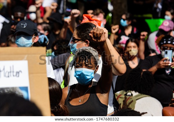 Miami Downtown, FL, USA - MAY 31, 2020: Woman leading a group of demonstrators on road. Group of female protesting for human rights and against racism