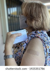 Miami, Fl, USA- Feb 26, 2021: Happy Masked Elderly Woman After Receiving Covid-19 Vaccine At Her Local Pharmacy Showing In Hand The  COVID-19 Vaccination Record Card By The CDC. 