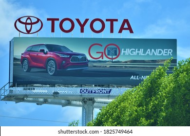 Miami, FL, USA - July 25, 2020: New Toyota Highlander Hybrid Car Model On Big Outdoor Highway Advertisement Billboard With Motor Company Brand Logo Symbol With Bright Blue Sky And Trees Nearby