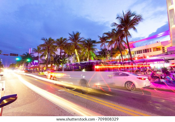MIAMI, FLORIDA - AUGUST 26, 2017: Cars speed down Ocean
Drive. The road is the main thoroughfare through South Beach,
Miami. Ocean Drive scene at night lights, cars and people having
fun,Miami beach. 