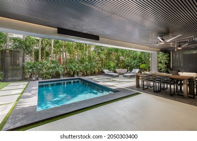 Miami, Florida, USA. April 3, 2021: Backyard Of A Minimalist Mansion With Swimming Pool, Greenery And Luxury Furniture.