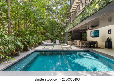 Miami, Florida, USA. April 3, 2021: Backyard Of A Minimalist Mansion With Swimming Pool, Greenery And Luxury Furniture.