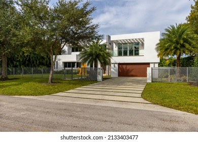 Miami, Florida, USA. November 16, 2021: Facade Of The Entrance To A American Dream House With Garage, Trees, Grass And A Blue Sky.