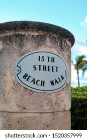 Miami , Florida/USA - September 25 2019: Stone Signpost With Retro Style Lettering On A Sign For The 15th Street Beach Walk In South Beach, With A Background Of Blue Sky And Palm Tree.