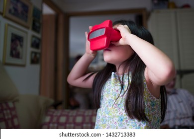 Miami, Florida/USA-03/16/2019: Girl Viewing Towards The Light, Tiny Transparent Reels Of 3-D Film Color Photographs Using A Special Format Of Sliding Cardboard Disks On A Stereoscopic Viewfinder Toy 