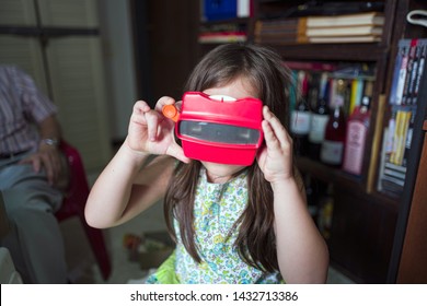 Miami, Florida/USA-03/16/2019: Girl Viewing Towards The Light, Tiny Transparent Reels Of 3-D Film Color Photographs Using A Special Format Of Sliding Cardboard Disks On A Stereoscopic Viewfinder Toy 