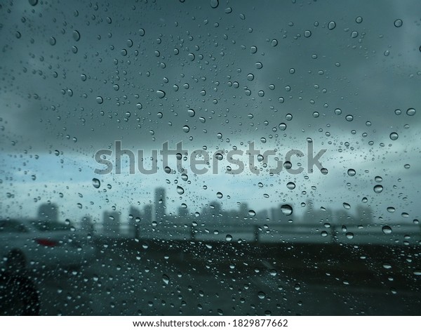 The Miami skyline, as seen\
through the window of a car on a rainy day, with raindrops on the\
glass