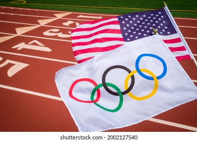 MIAMI, USA - AUGUST, 2019: An Olympic and American flag flutter together above a red athletics track.