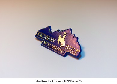 Miami, USA - October 10, 2020: Jackson Hole, Wyoming Text Logo On Plastic Blue Souvenir Pin Memorabilia With Western American Country Cowboy Riding On Horse Through The Grand Teton Mountain Landscape