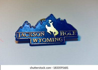 Miami, USA - October 10, 2020: Jackson Hole, Wyoming Text Logo On Plastic Blue Souvenir Pin Memorabilia With Western American Country Cowboy Riding On Horse Through The Grand Teton Mountain Landscape