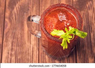 Michelada beer with tomato juice. Clamato with beer on wooden table. Mexican drink.