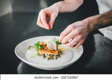 Michelin chef preparing fish food on dark table, hands of cook  - Powered by Shutterstock