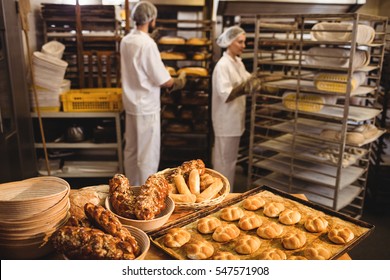 Michetta and sweet food on a table while male and female baker working in background at bakery shop - Powered by Shutterstock