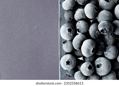 Micro of blueberries in glass container with copy space on grey background. Micro photography, fruit, texture and colour concept.