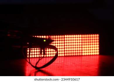 Micro controller is controlling an electronic component on the background. LED dot matrix display board illuminating red color light