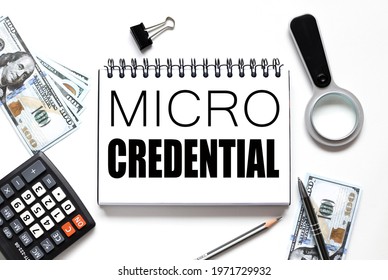 MICRO CREDENTIALS .Education Concept. Notebook On White Workspace. Near The Notepad Dollar Bills And A Calculator