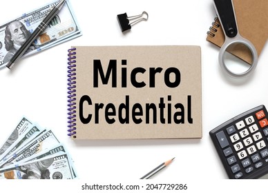 Micro Credentials. Notebook On White Workspace. Near The Notepad Dollar Bills And A Calculator