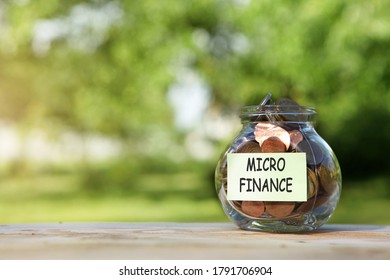 Micro Finance. Glass Jar With Coins, On A Wooden Table, On A Natural Background.Investment And Finance Concept.