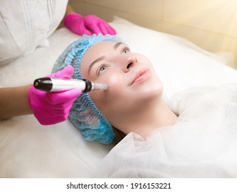 Micro needling therapy. Professional cosmetologist is doing procedure of microneedling. Fractional Needle mesotherapy with dermapen close up. Beauty salon, cosmetology clinic. Face Skin Care treatment