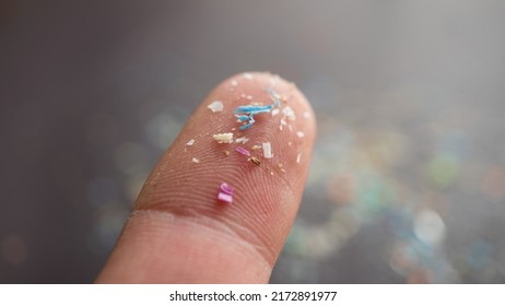 Micro Plastic Particles On A Human Finger For Scale. Concept For Water Pollution And Global Warming.