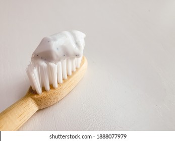 Micro plastic particles in a smear of toothpaste on a wooden toothbrush. Representation of the micro plastic problem in personal care products that damage nature.