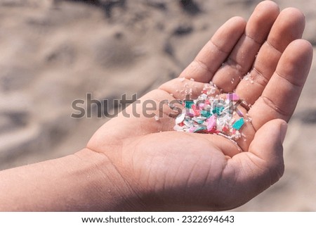 Micro plastics or Microplastics found on the beach on a person's hand on Mexico, sea sand in the background.