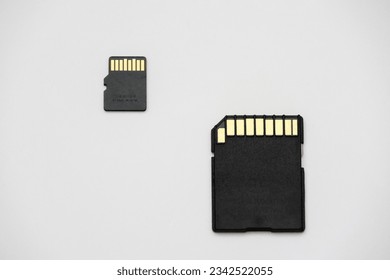 A micro SD Sandisk memory card and SD card on a white surface