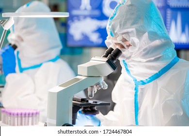 Microbiologist Biotechnology Researcher Or Medical Worker Team Look Microscope In The Lab With Isolation Gown Or Protective Suits And Surgical Face Mask