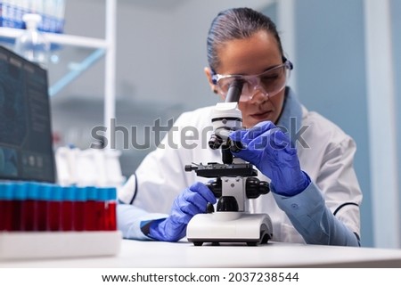 Microbiologist doctor woman analyzing vaccine results using medical microscope researching bacteriology infection diagnostics against coronavirus. Specialist doctor working in biotechnology laboratory