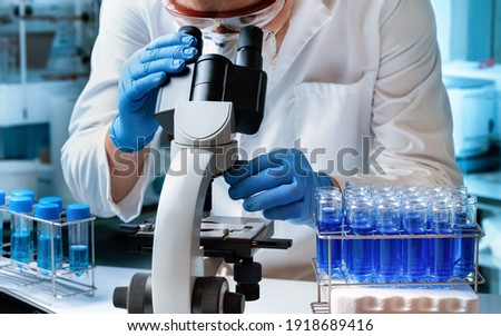Microbiologist examining biological samples with a microscope and an inoculation loop in the laboratory. Microscopist scientist working with micro samples in the microbiology lab 