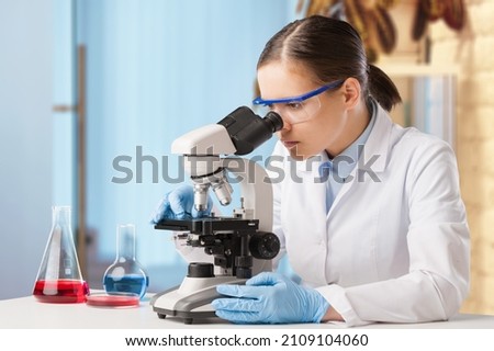 Microbiologist examining biological samples with a microscope in the laboratory.