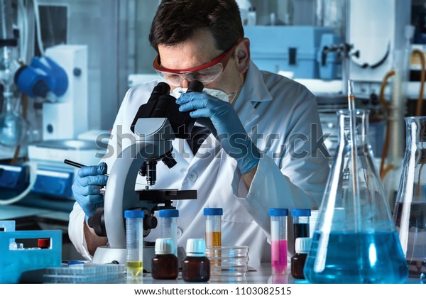 microbiologist\
working with sample in biomedical laboratory / microscopist\
analyzing samples in the\
microscope