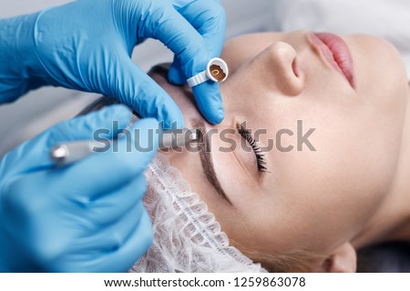 Microblading in the beauty salon. Beautiful girl on the cosmetic procedure for the treatment of eyebrows. Eyebrow micro-processing. Processing Manipula.