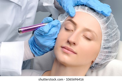 Microblading eyebrows. Cosmetologist making permanent makeup. Attractive woman getting facial care and tattoo at beauty salon